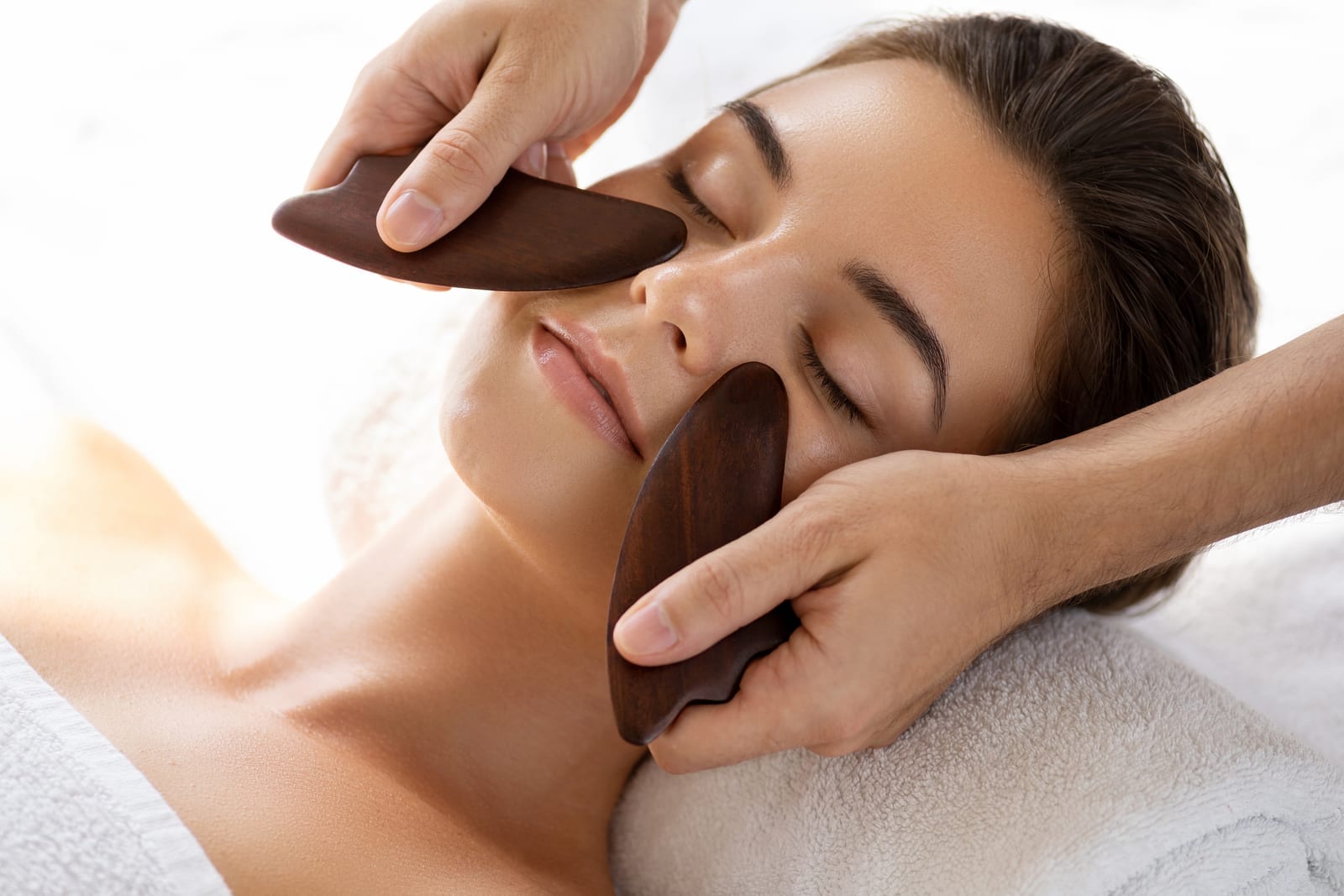 Gua Sha facial treatment with two wooden tools